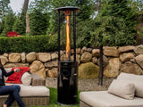 Woman sitting on outdoor furniture, pointing remote control at Illume Propane Patio Heater