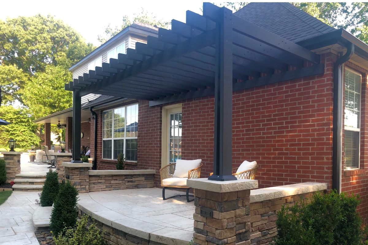 UGC Photo of Custom Pergola in backyard. Pergola is attached to a brick house and placed on top of pavers.