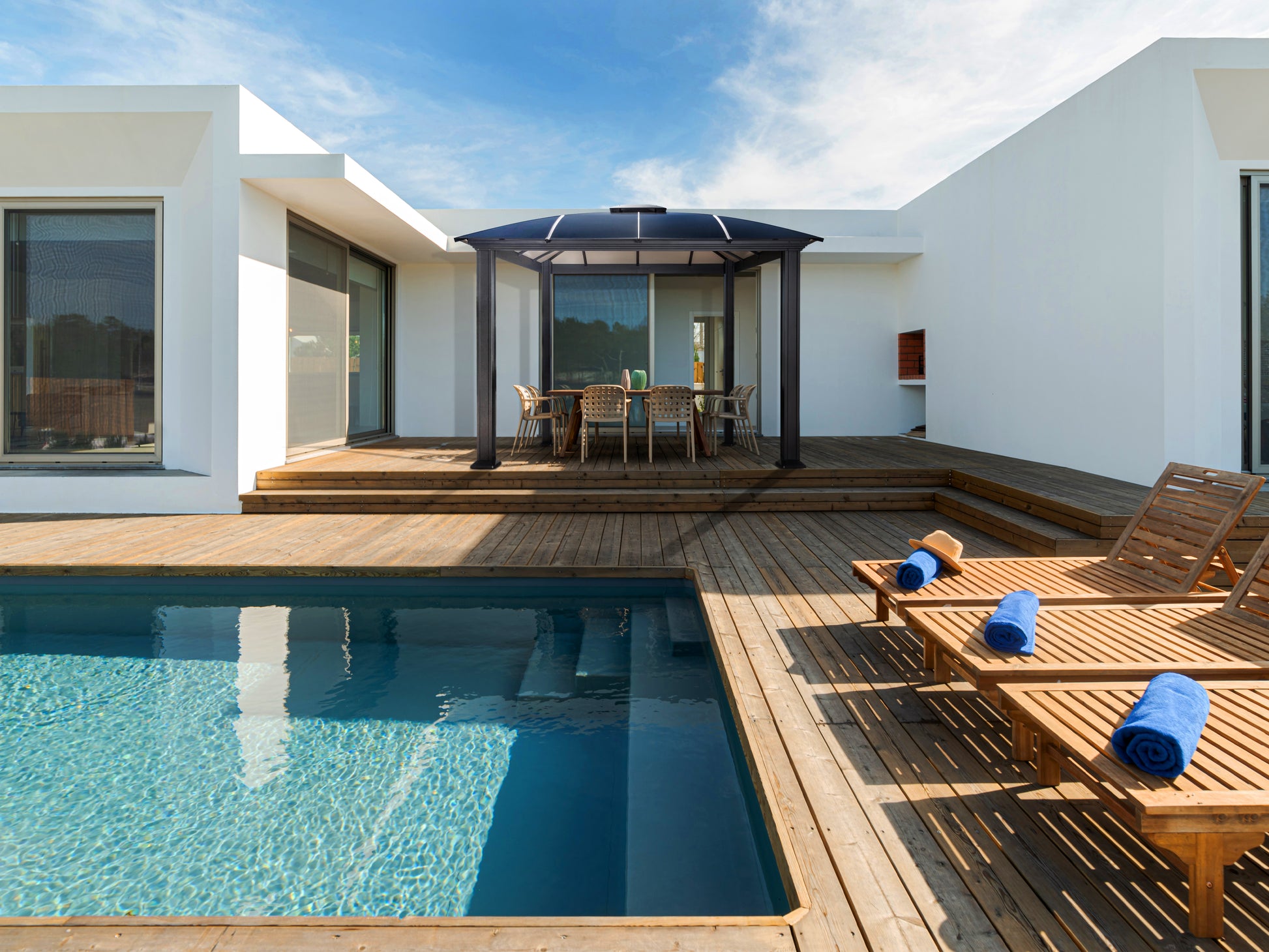 Cambridge Hard Top Gazebo on wooden deck behind a pool.