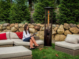 Woman seated on outdoor couch in front of Shine Patio Heater with visible Flame.