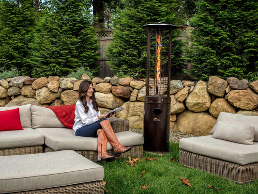 Woman seated on outdoor couch in front of Shine Patio Heater with visible Flame.