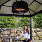 Glow Pendent Heat Lamp hanging from gazebo. Woman sitting underneath with glass of wine.