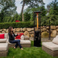 Woman sitting on outdoor furniture, pointing remote control at  Illume Propane Patio Heater