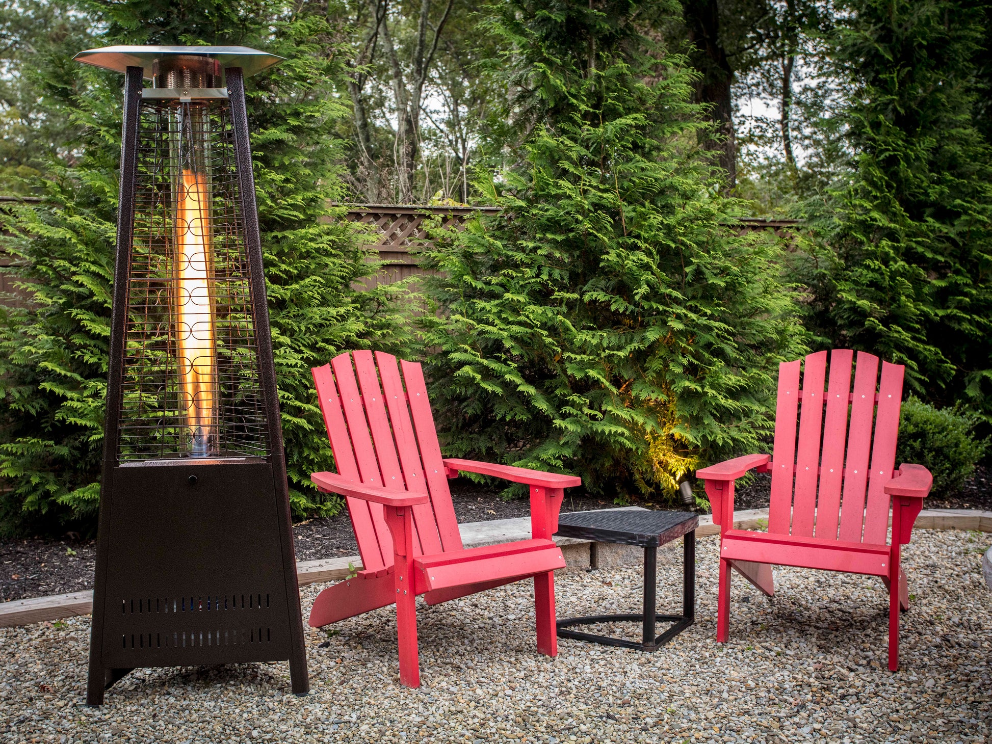 Boost Propane Patio Heater in backyard with red Adirondack chairs in lush backyard